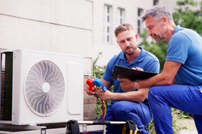HVAC technicians reviewing an outdoor air conditioning unit in Castle Rock, CO